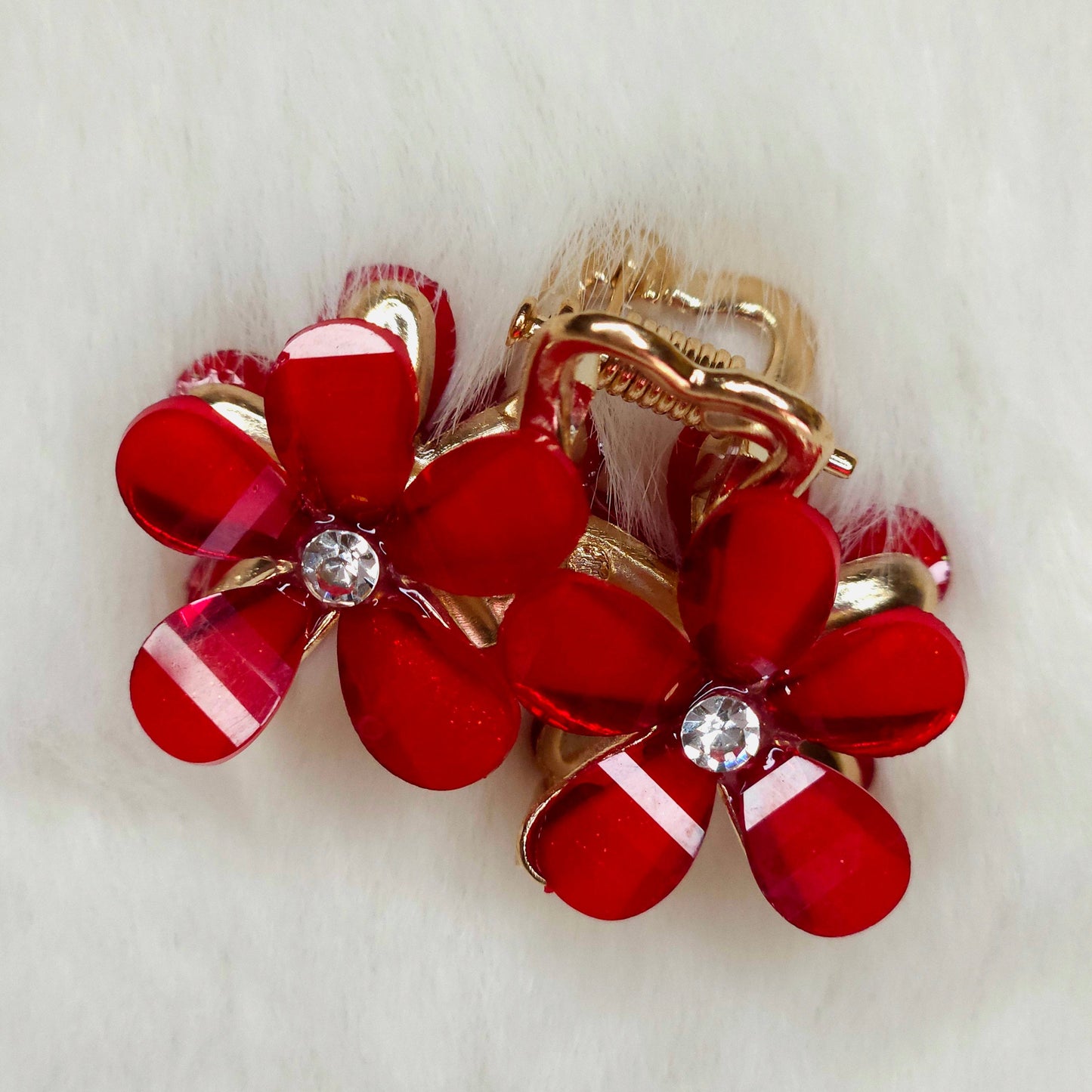 Red flower-shaped hair clip with gold accents on a white background