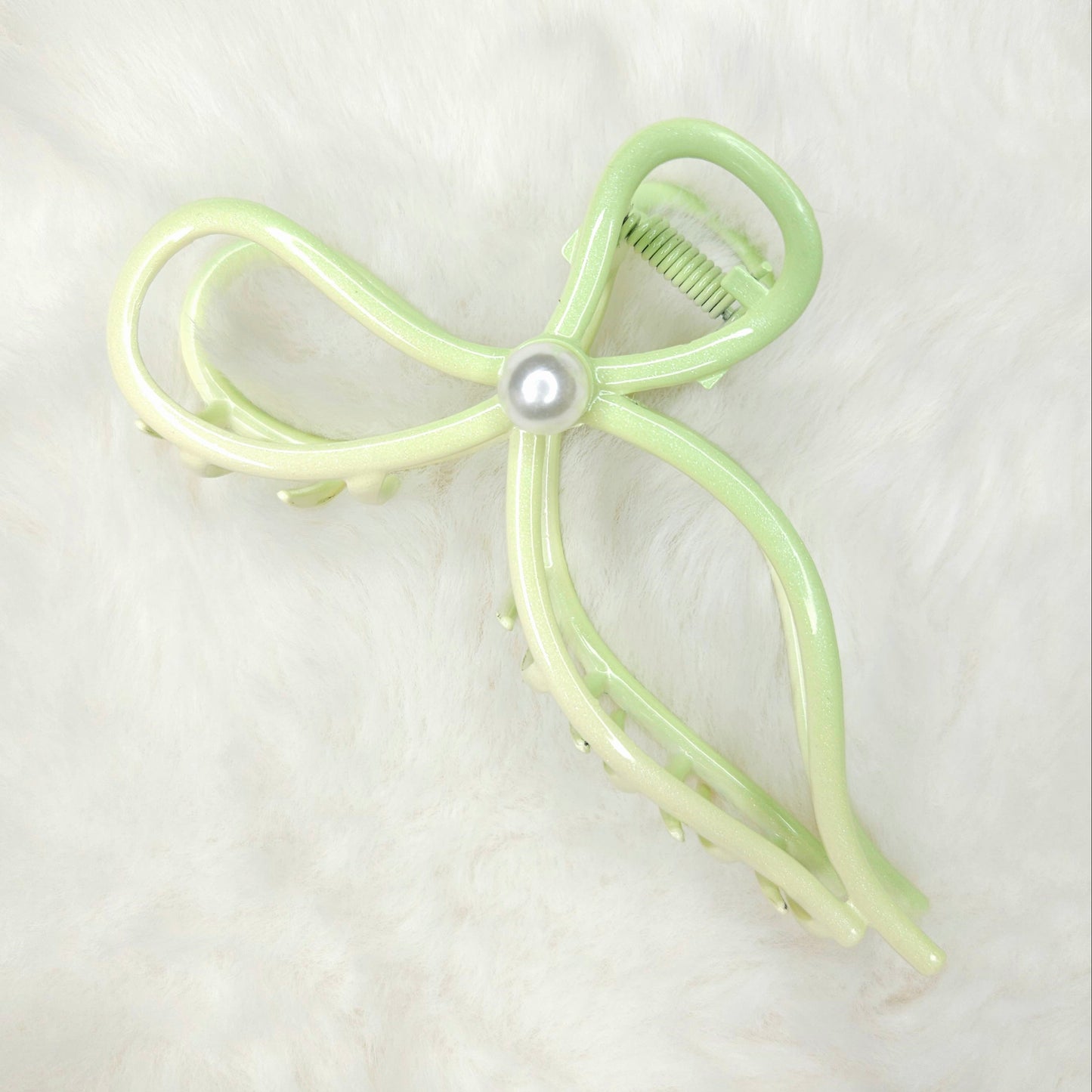 Light green bow-shaped hair clip with a pearl on a white background