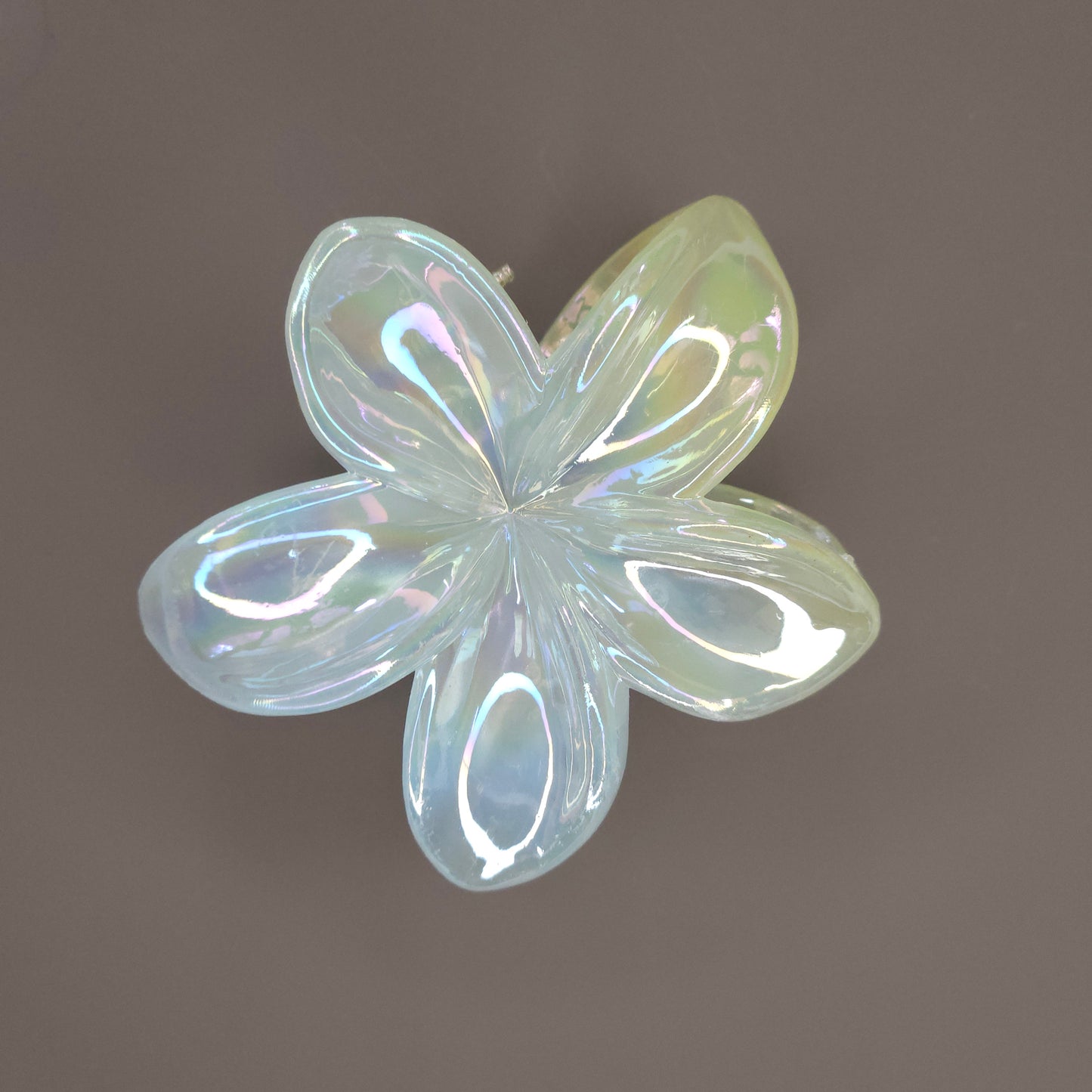 A medium-sized, layered flower hair claw clip in a pastel mint green, featuring a dual-shade glimmer that shifts in color, giving the surface a high-shine, iridescent look.