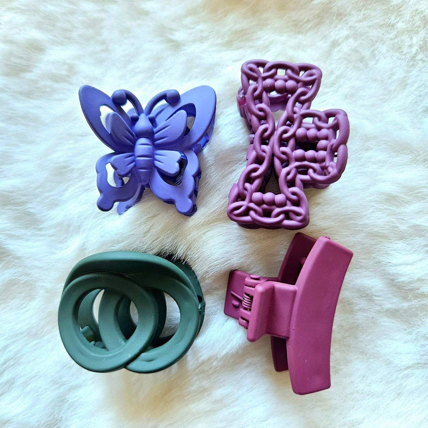 Four butterfly-shaped silicone claw clips on a white fur background