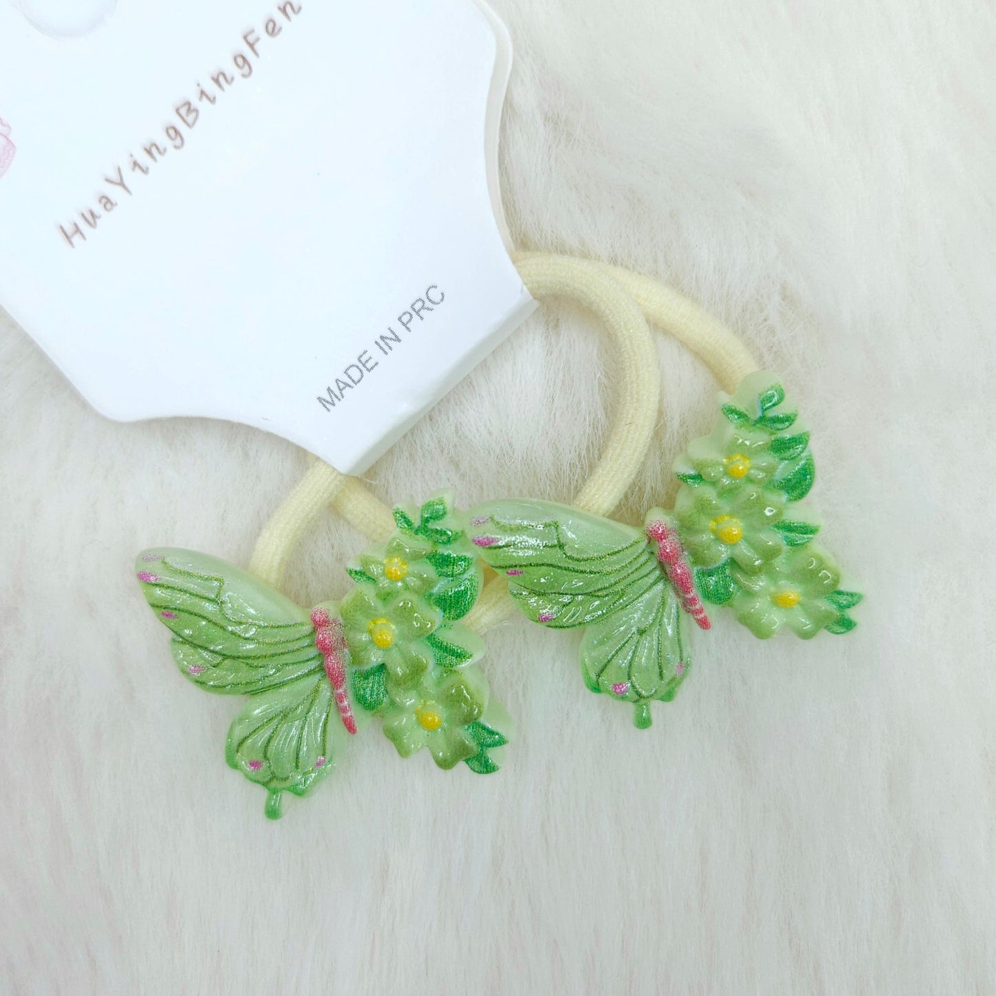 Green butterfly-shaped hair ties on a white background with a brand label.
