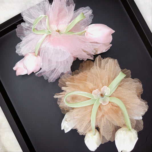 Two decorative hair accessories with tulle and flowers on a black tray.