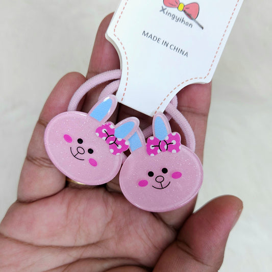 Pink bunny-shaped hair ties with a visible brand label held in a hand.