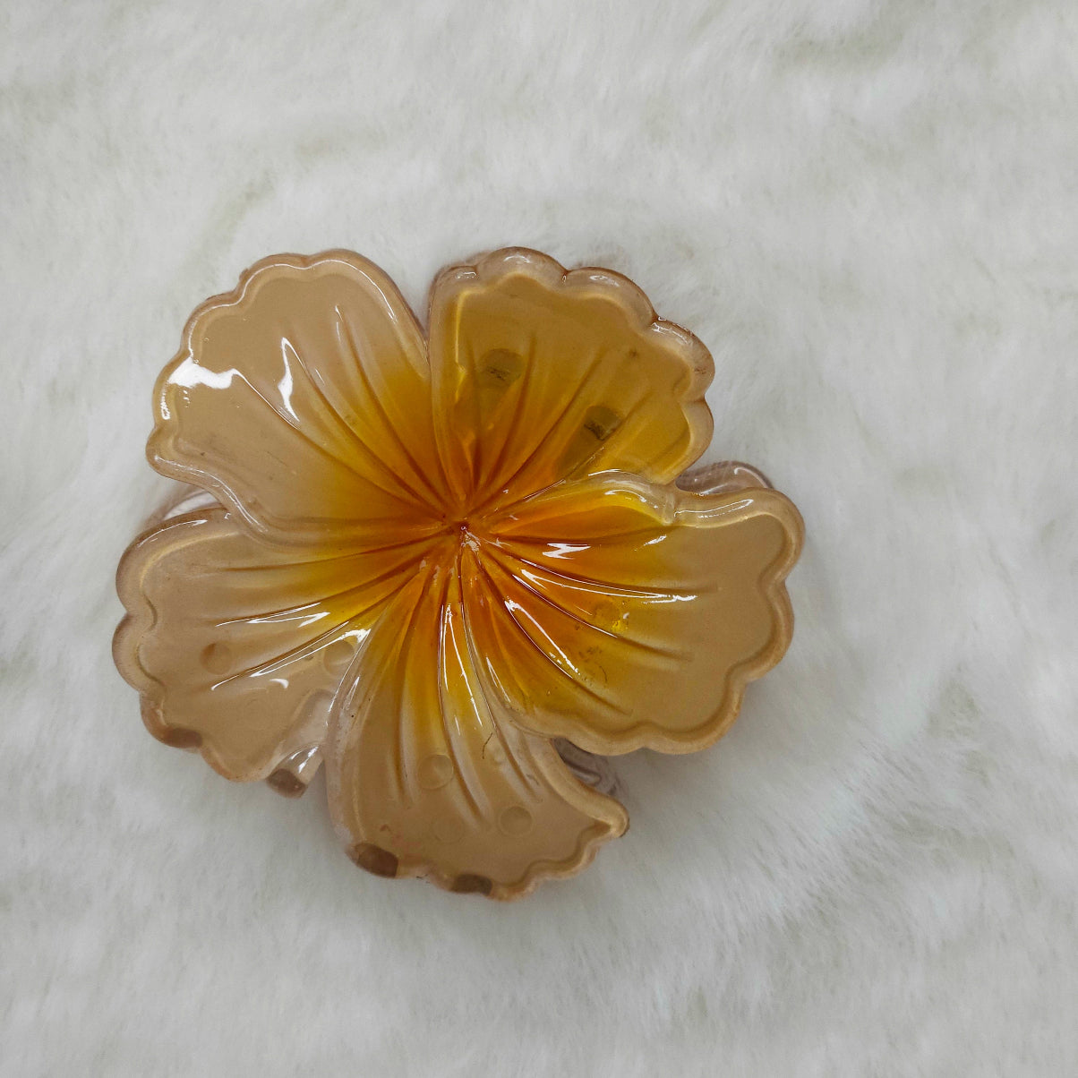 Decorative amber-colored hibiscus flower shaped hair claw clips on a white background.