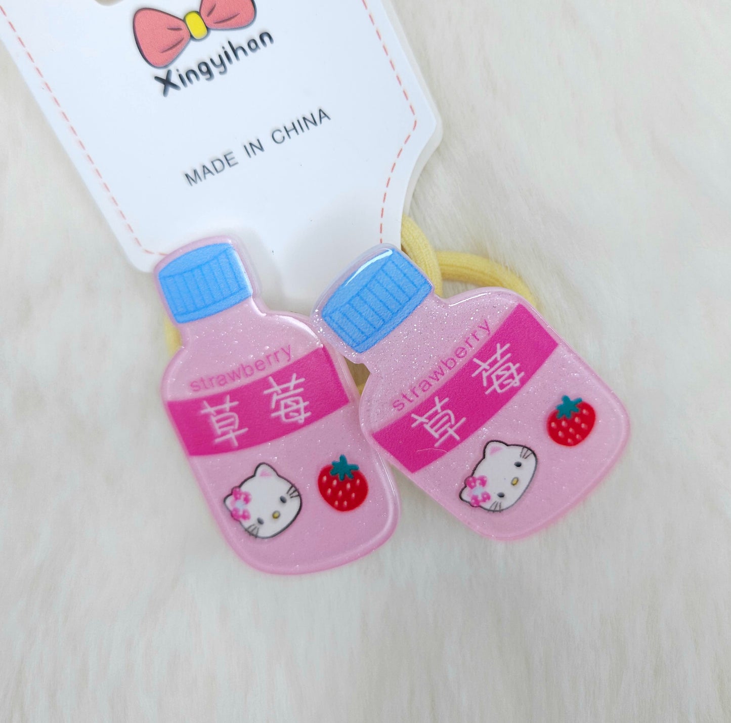 Two pink bottle-shaped hair ties with Hello Kitty design on a white background