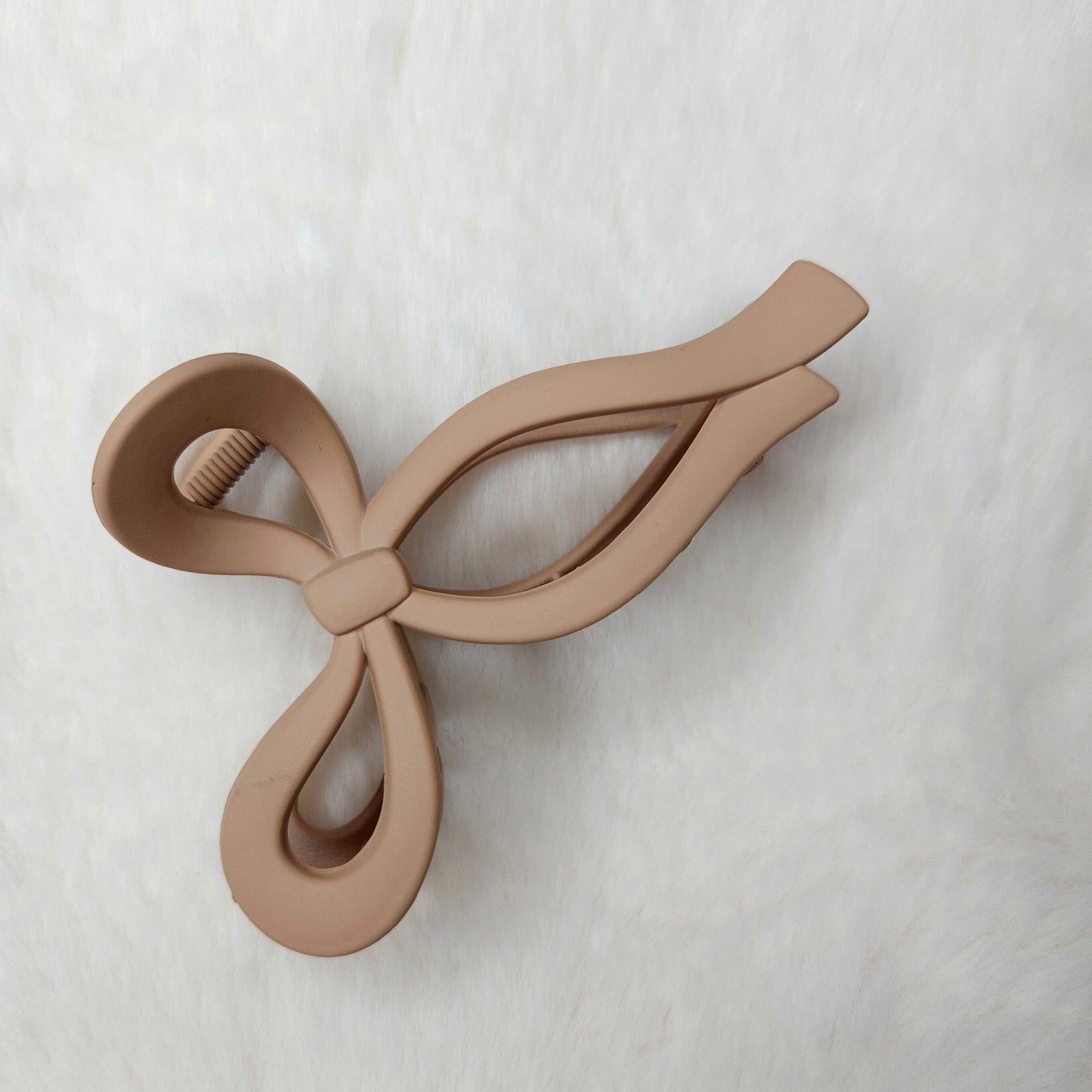 Beige bow-shaped hair claw clip on a white background