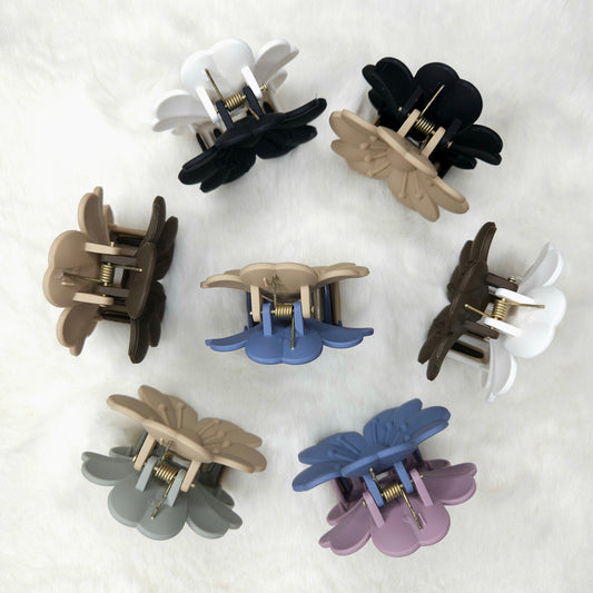 Set of flower-shaped hair claw clips in various colors on a light background