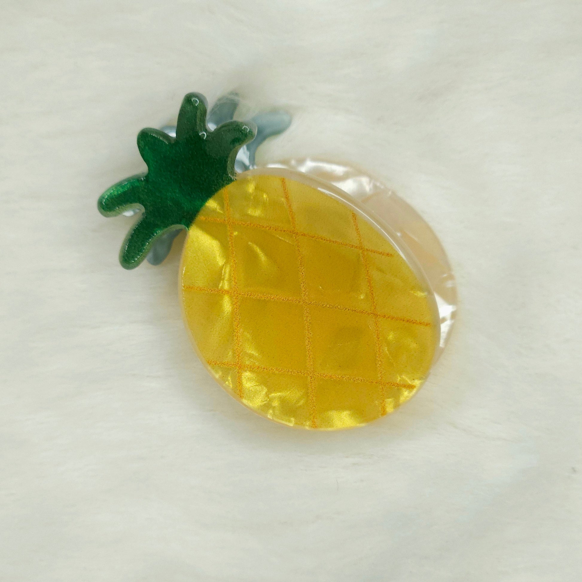 Pineapple-shaped hair claw clip with a green stem on a white background