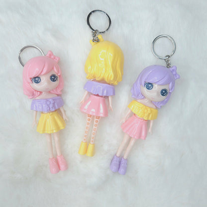 Three colorful keychains shaped like small dolls with pastel hair colors on a white background.