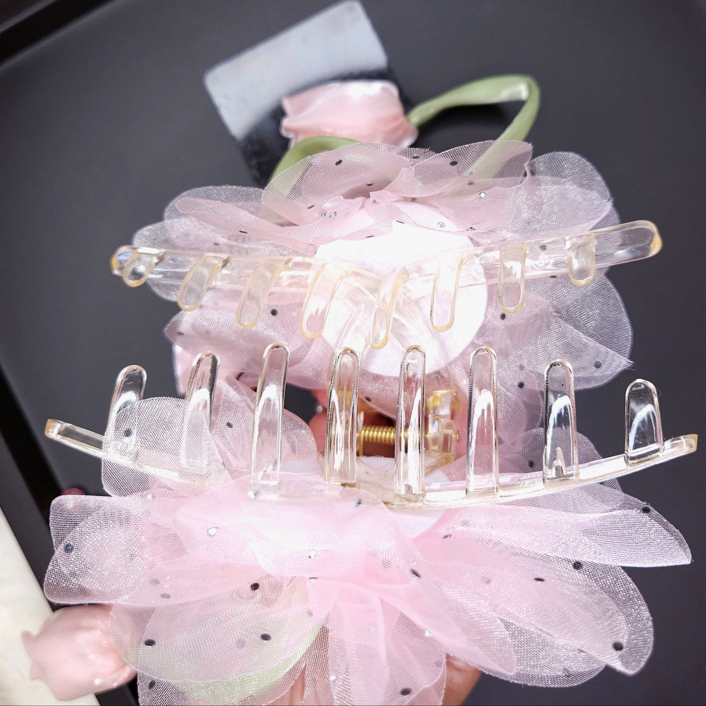 Pink floral hair clip on a black tray