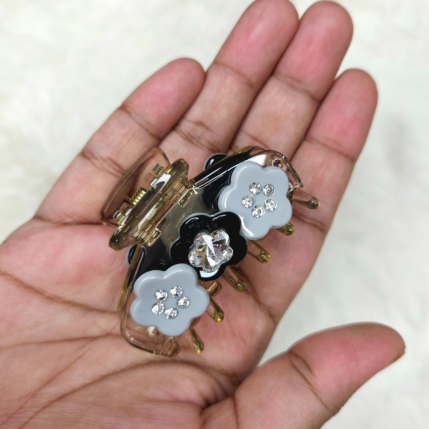 Hand holding a small decorative item with floral designs on a white background
