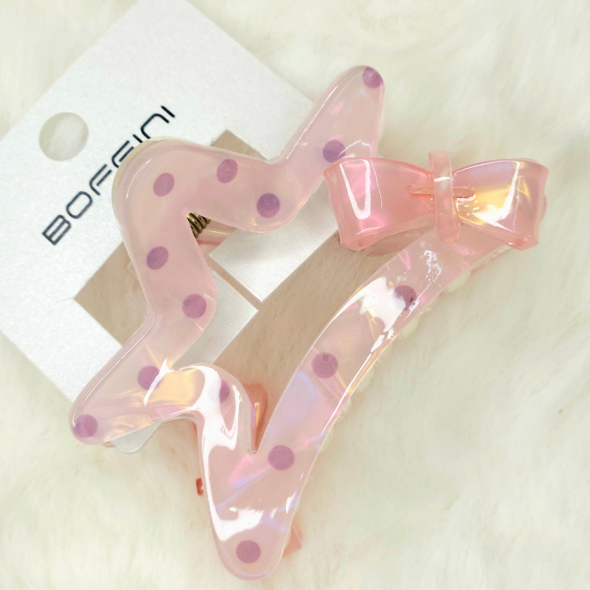 Pink hair clip with polka dots on a white background