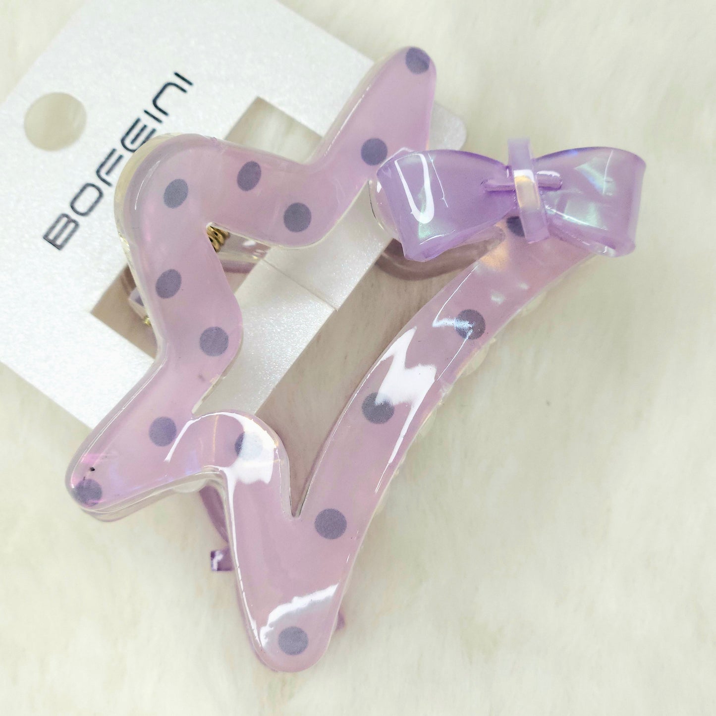Purple hair clips with polka dots and a bow on a white background