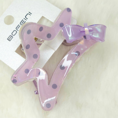 Purple hair clips with polka dots and a bow on a white background