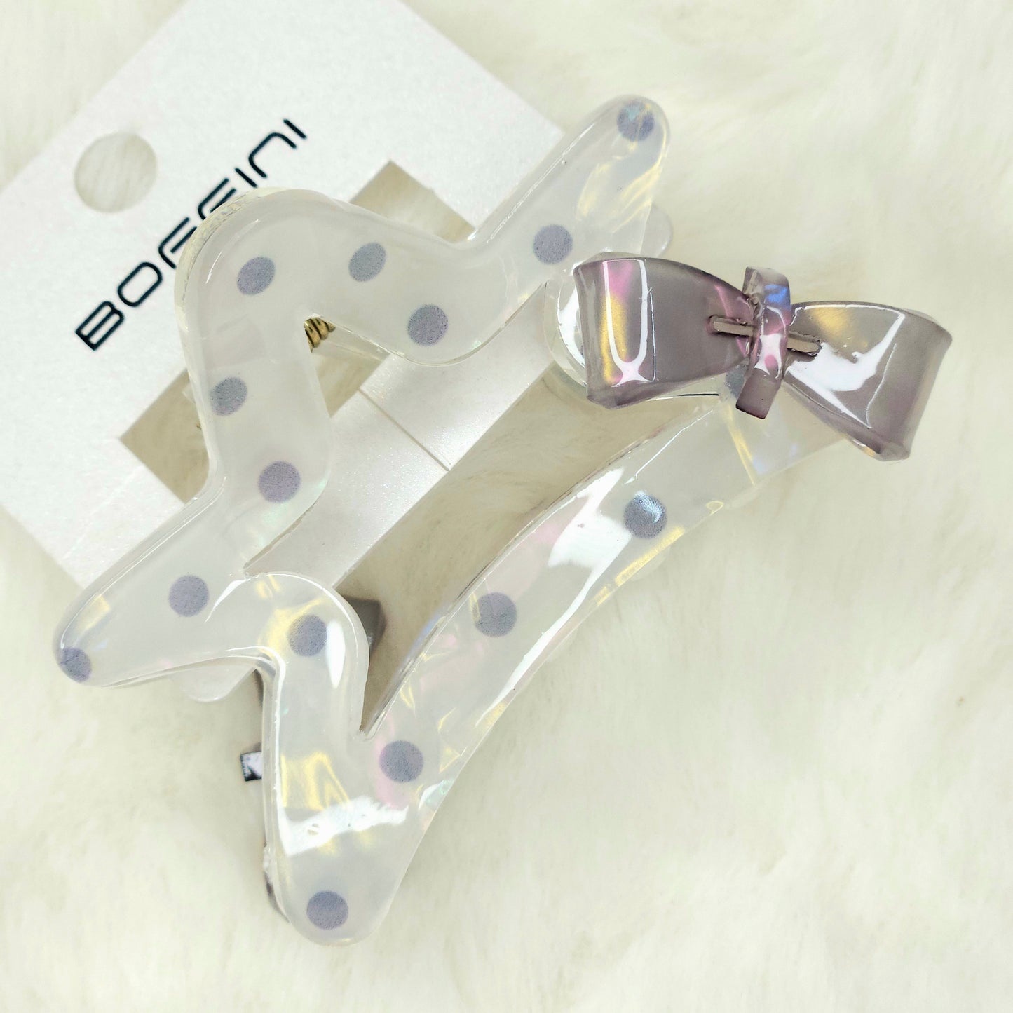 Clear hair clips with blue polka dots and a silver bow on a white background