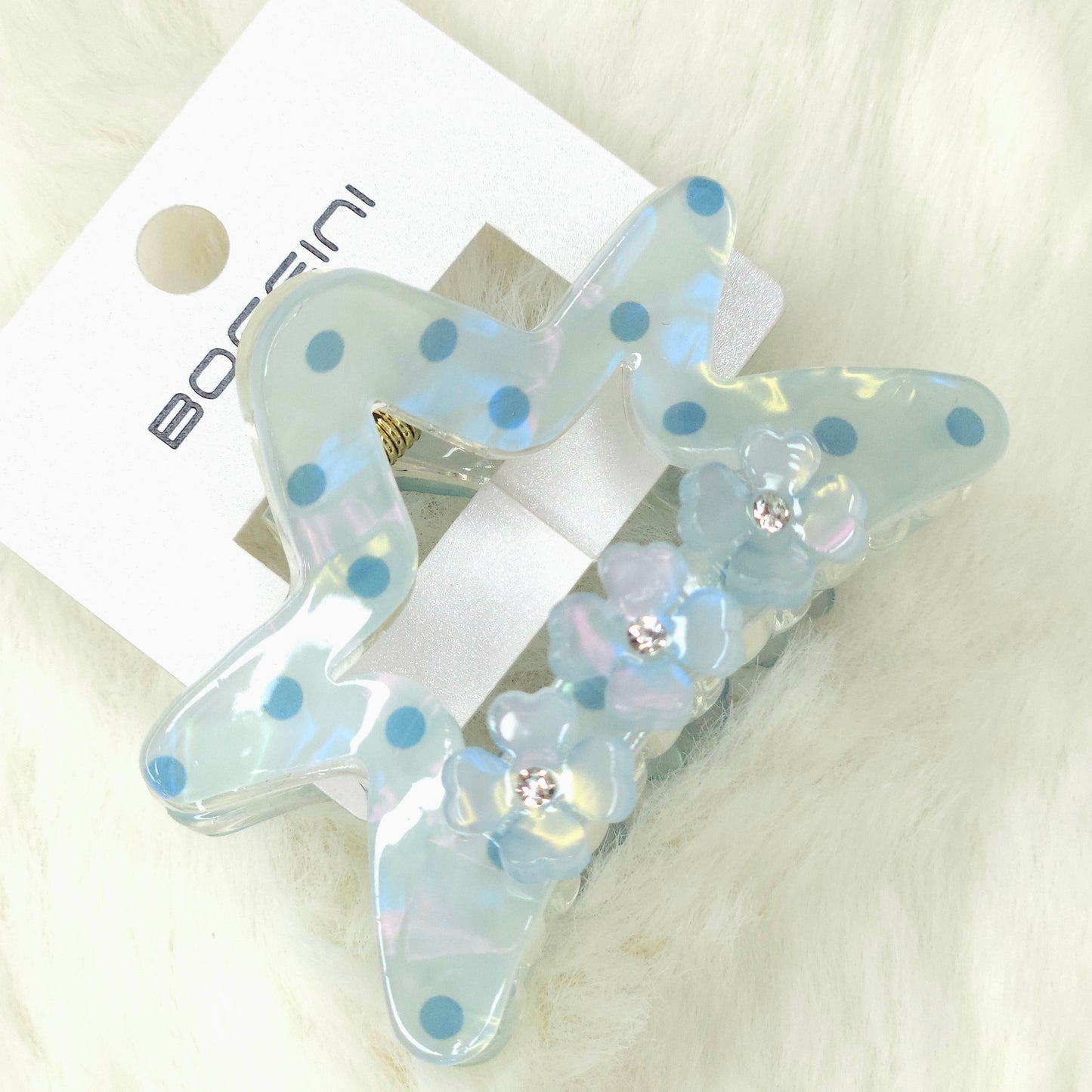 Clear hair clip with blue polka dots and rhinestones on a white background