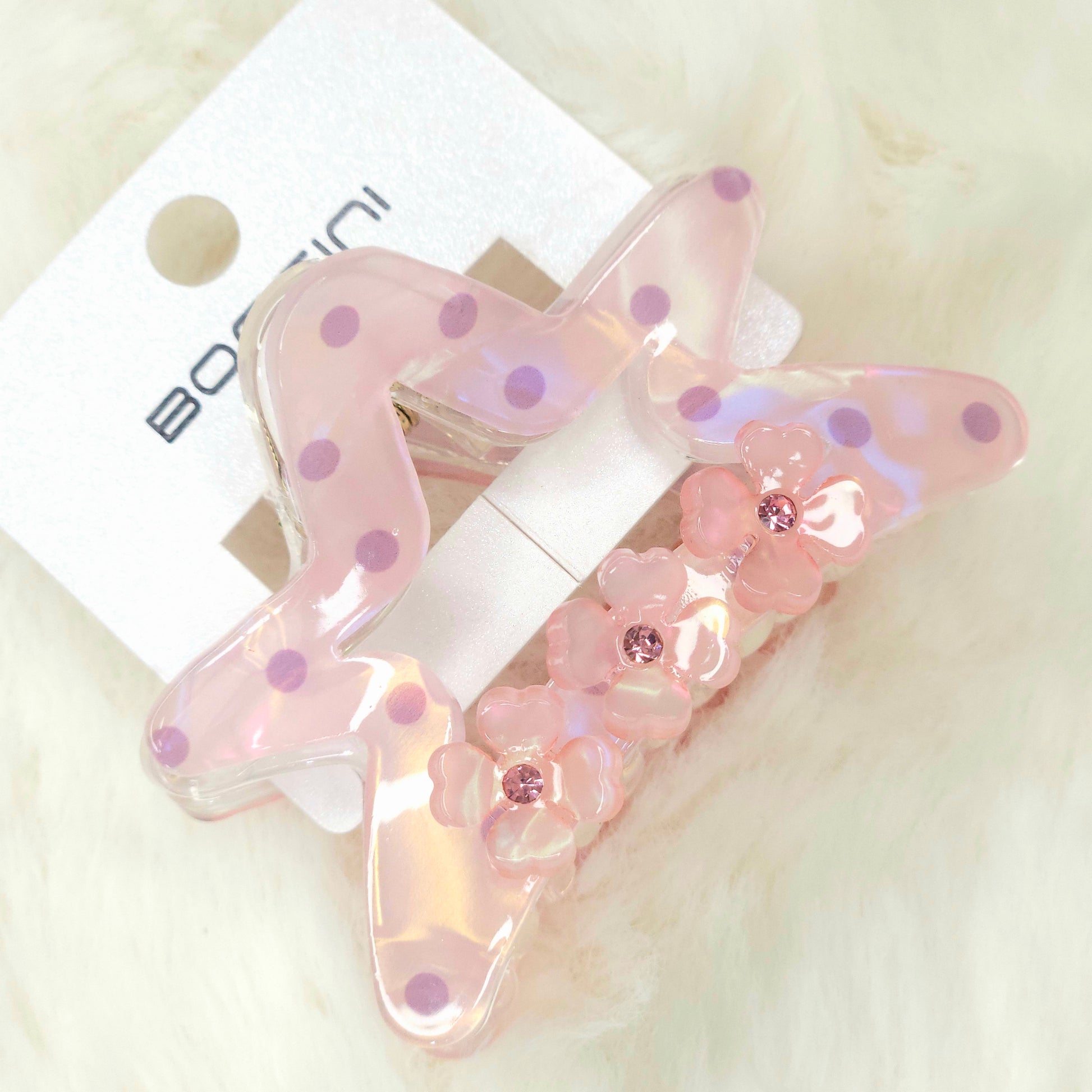 Pink butterfly hair clip with floral details on a white background