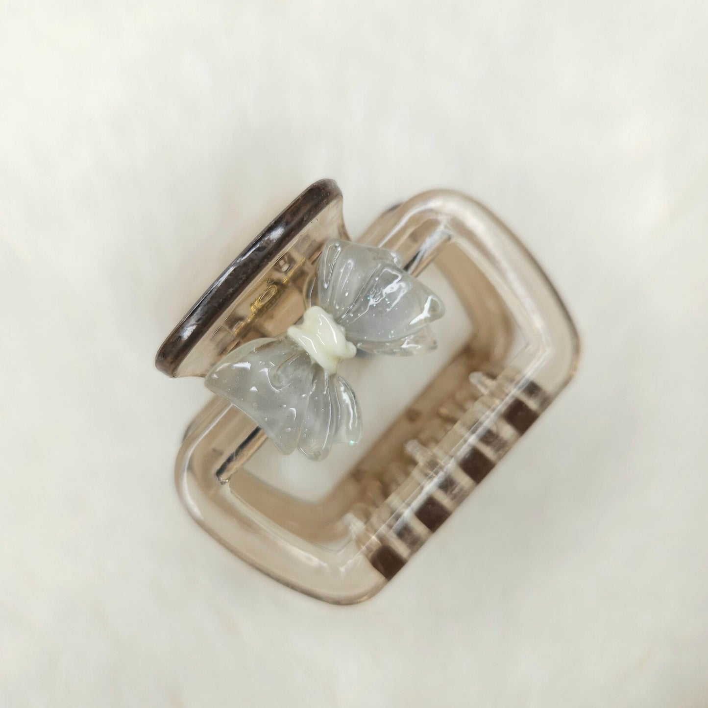 Clear butterfly-shaped hair claw in a silver case on a light background