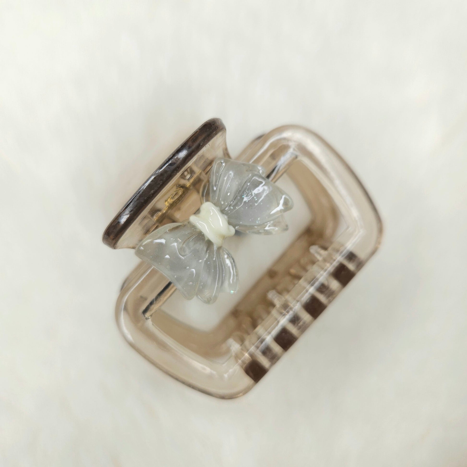 Clear butterfly-shaped hair claw in a silver case on a light background