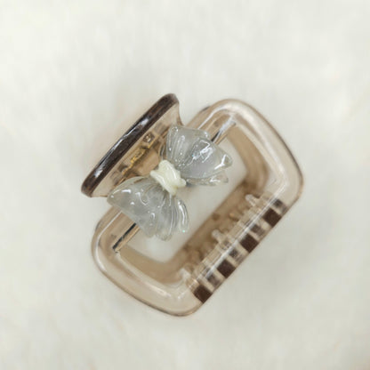 Clear butterfly-shaped hair claw in a silver case on a light background