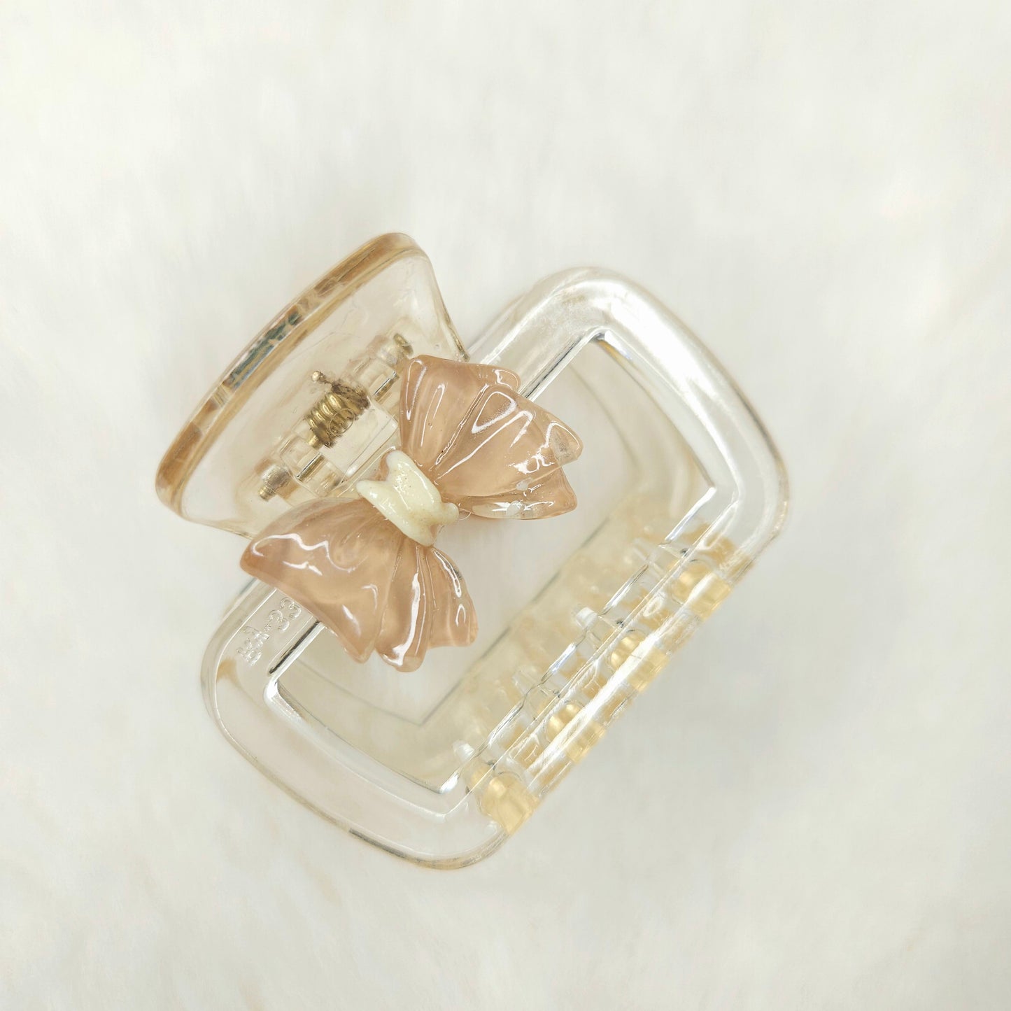 Clear hair clip with beige butterfly attachments on a white background