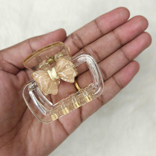 Clear plastic clip with butterfly design held in a hand against a white background