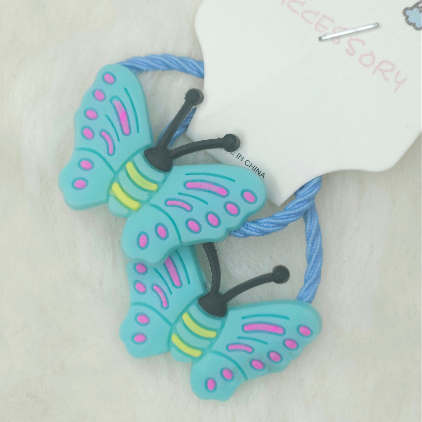 Butterfly-shaped hair tie on a mannequin arm with a white background