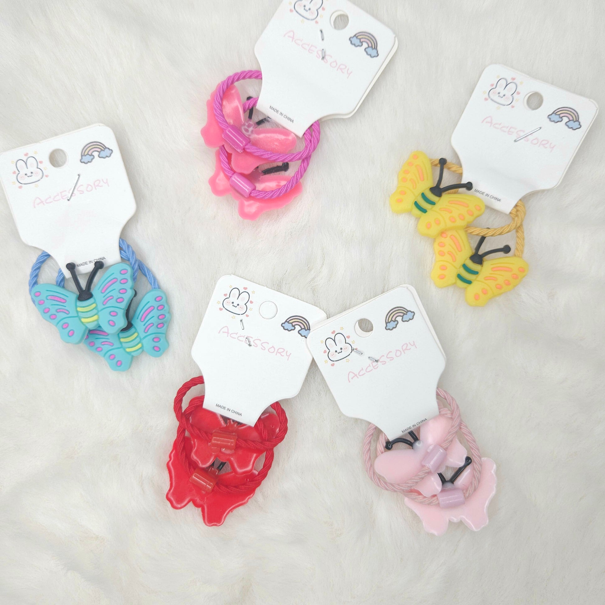Colorful hair ties with butterfly designs on white tags against a light gray background