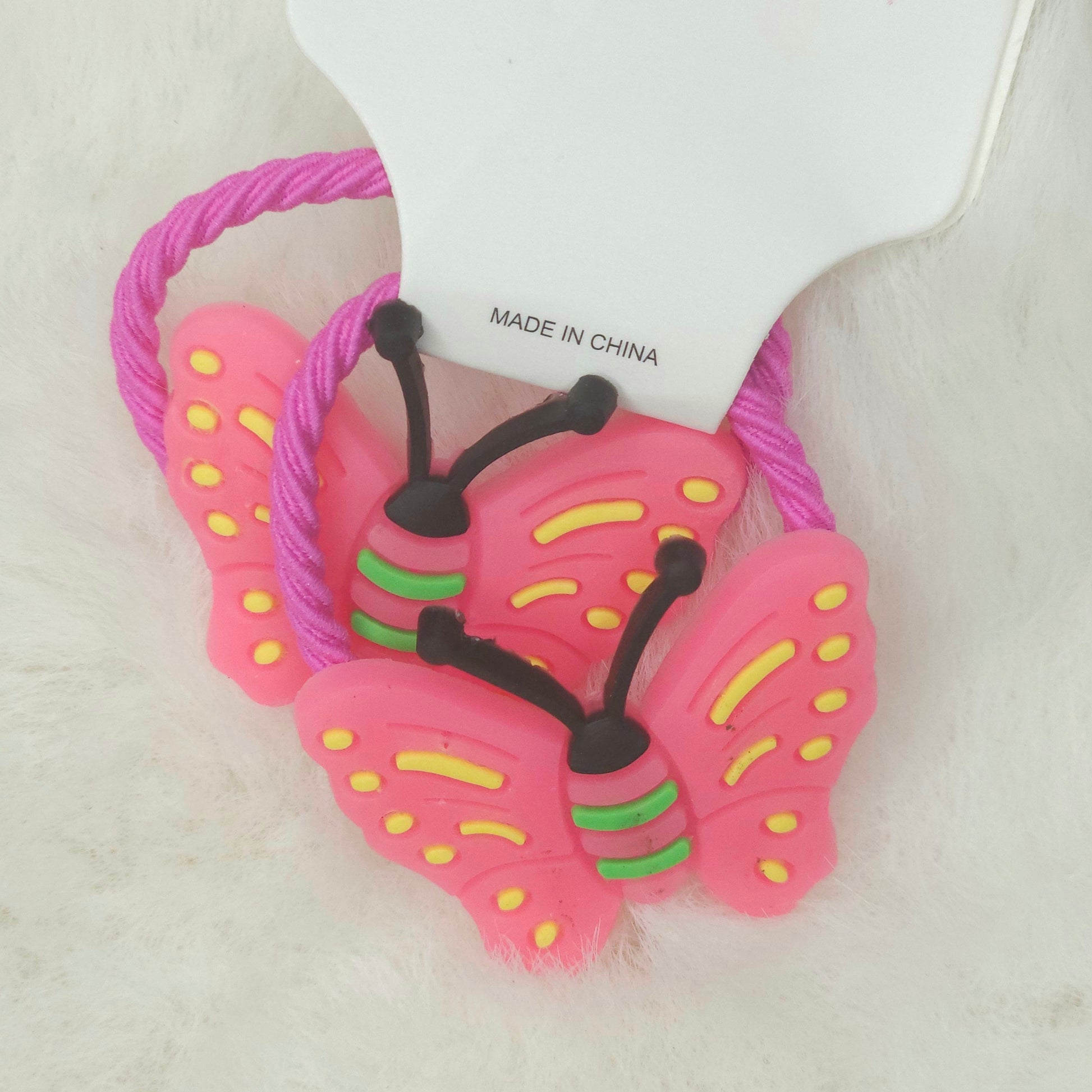 Pink butterfly-shaped hair ties with a visible 'Made in China' label on a white background