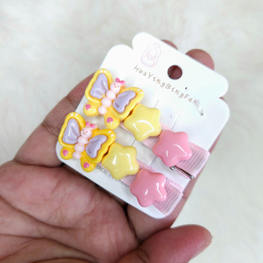 Set of butterfly and star-shaped hair clips on a white card held by a hand.
