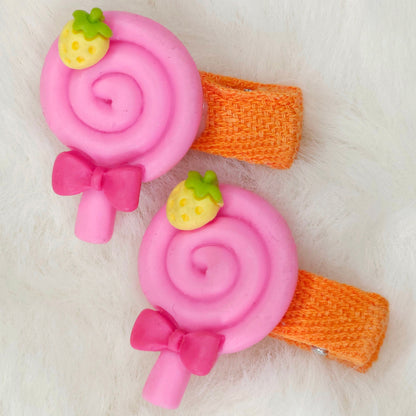 Two pink lollipop-shaped hair clips with orange bands on a white background