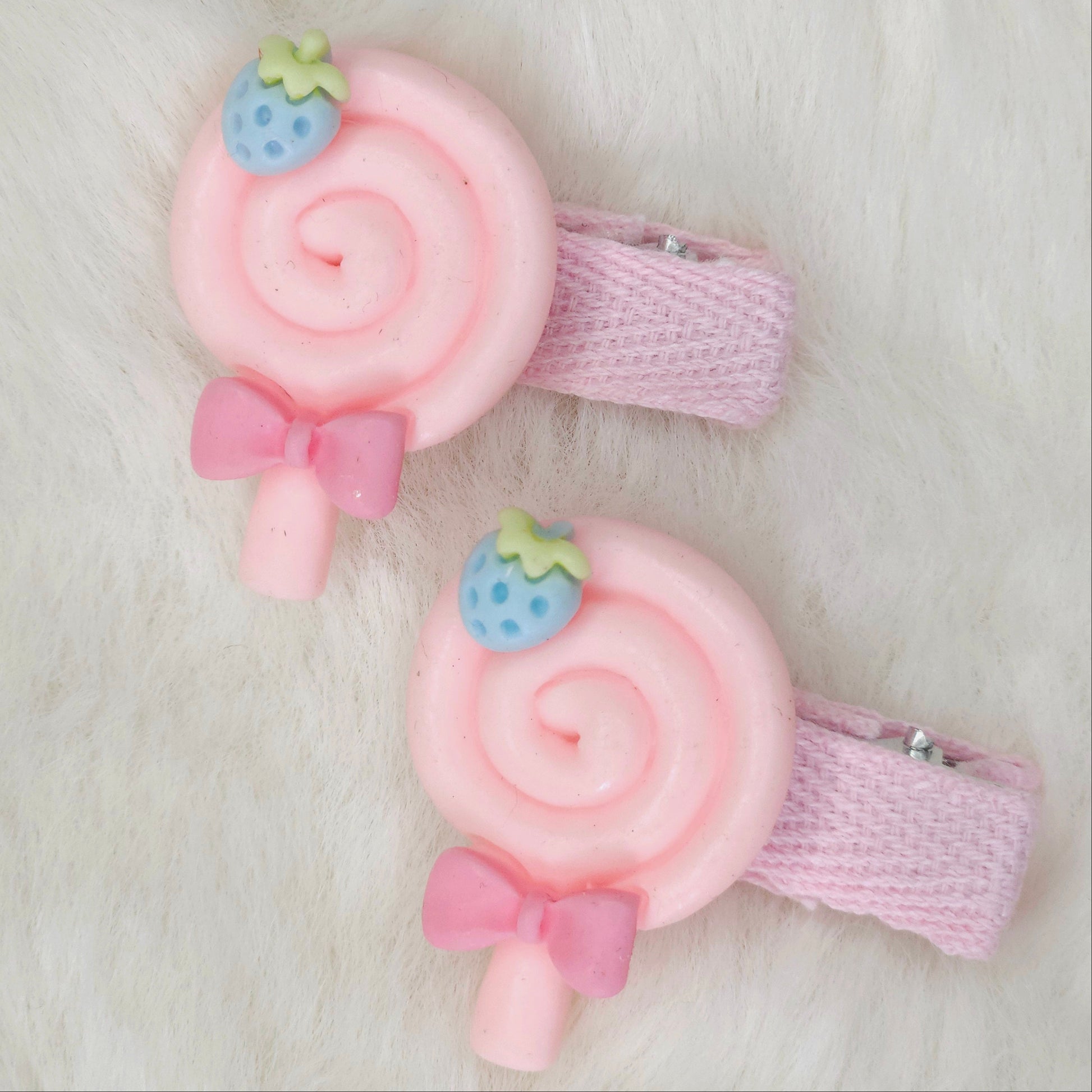 Two pink hair clips with candy design on a light background
