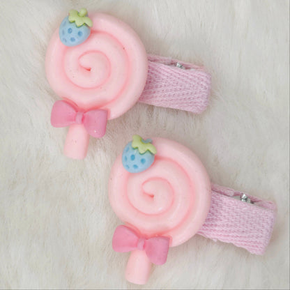 Two pink hair clips with candy design on a light background