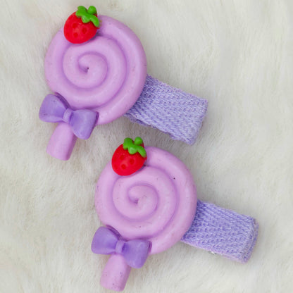 Purple lollipop-shaped hair clips with strawberry decorations on a white background