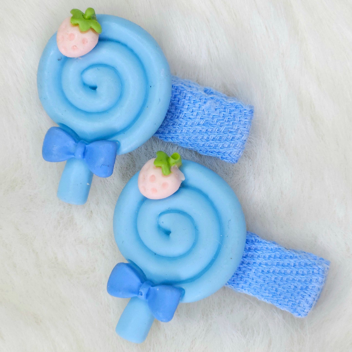 Two blue spiral hair clips with bows on a white background