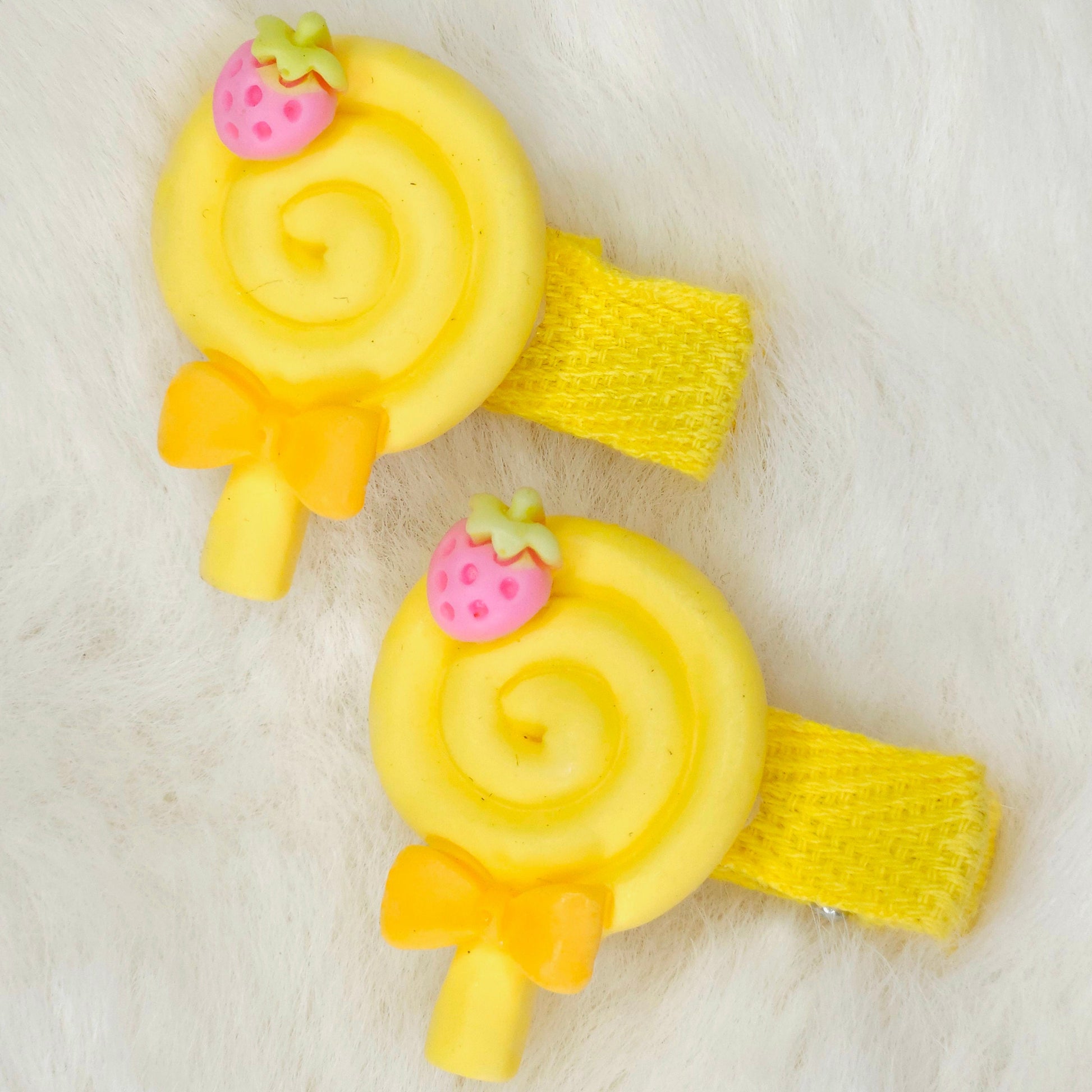 Two yellow spiral hair clips with strawberry accents on a white background