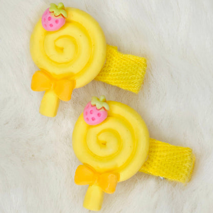 Two yellow spiral hair clips with strawberry accents on a white background