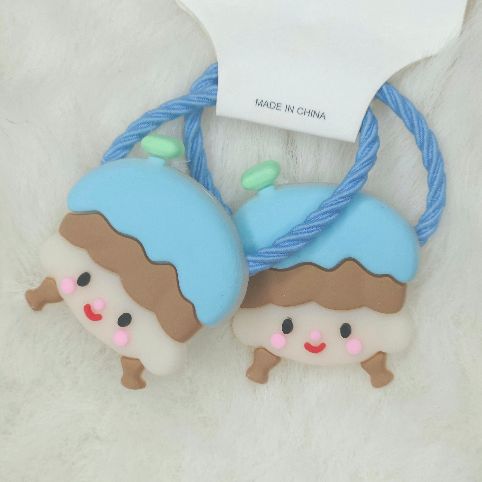 Two cute character-themed hair ties with a 'Made in China' tag on a light background