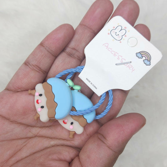 Hand holding two small blue and brown plush toys with a tag on a light background