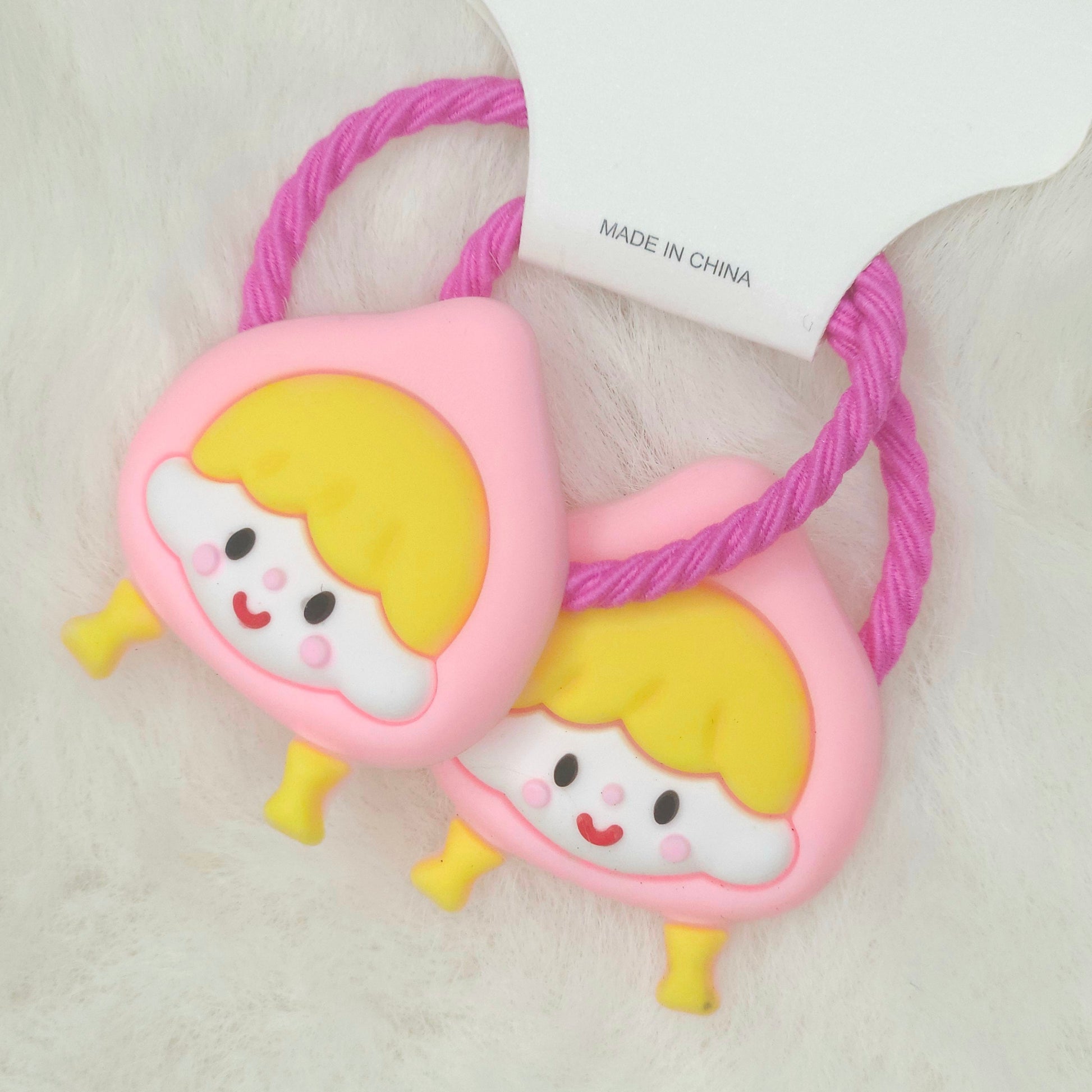 Two pink hair ties with cartoon character ends on a white background