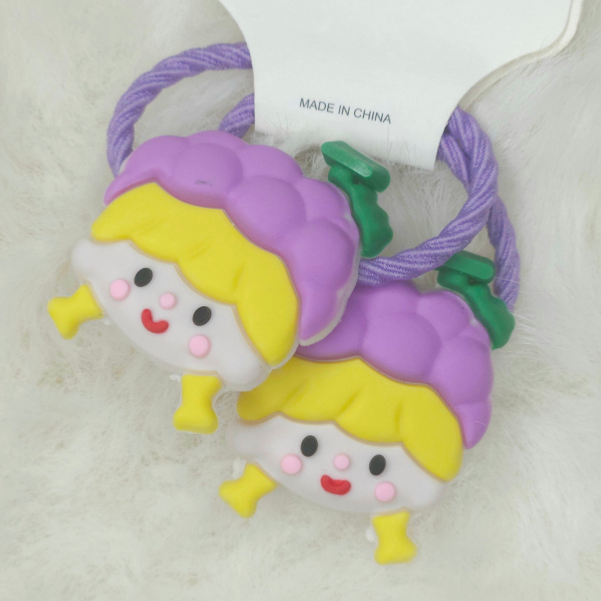 Two purple hair ties with cartoon character ends on a white background
