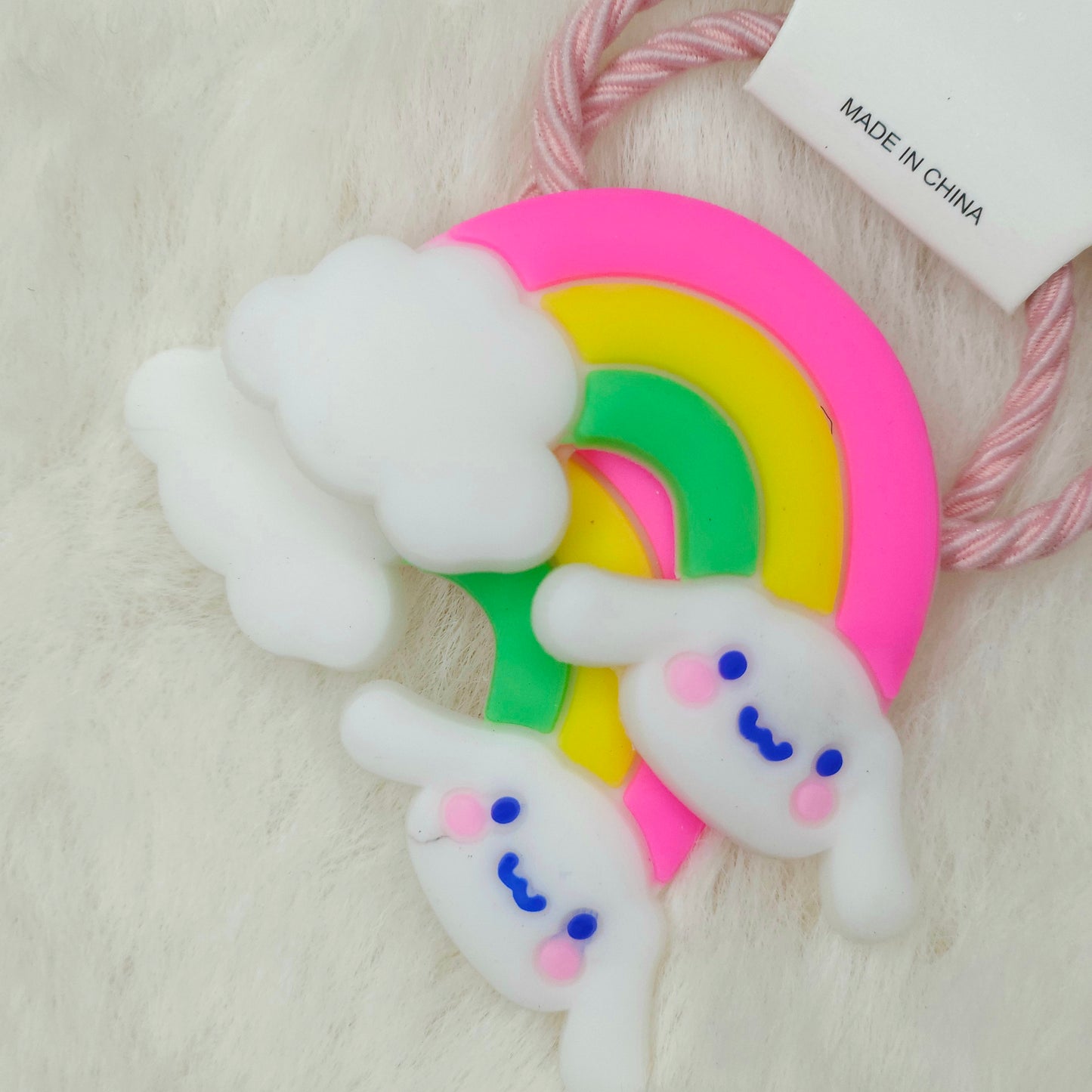 Colorful rainbow-shaped hair tie with cloud designs on a white background
