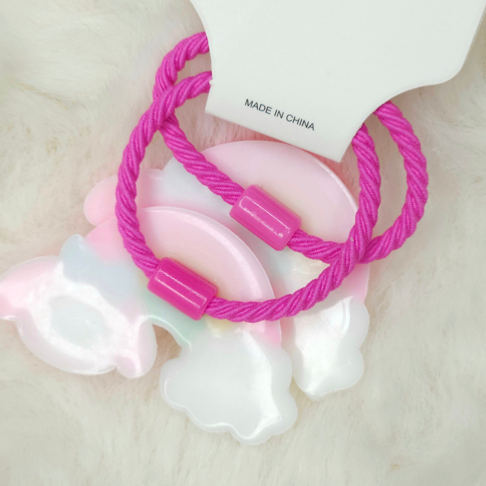 Pink hair ties with a white pacifier on a light background