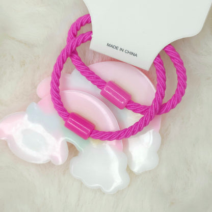 Pink hair ties with a white pacifier on a light background
