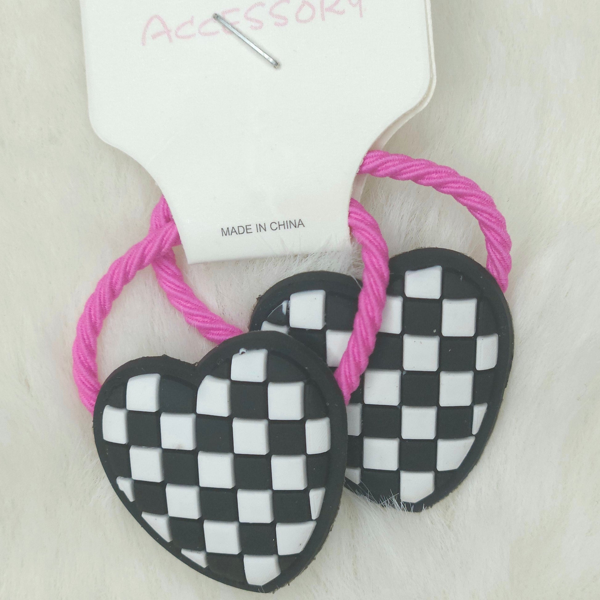 Heart-shaped checkered accessories with pink strings on a white background