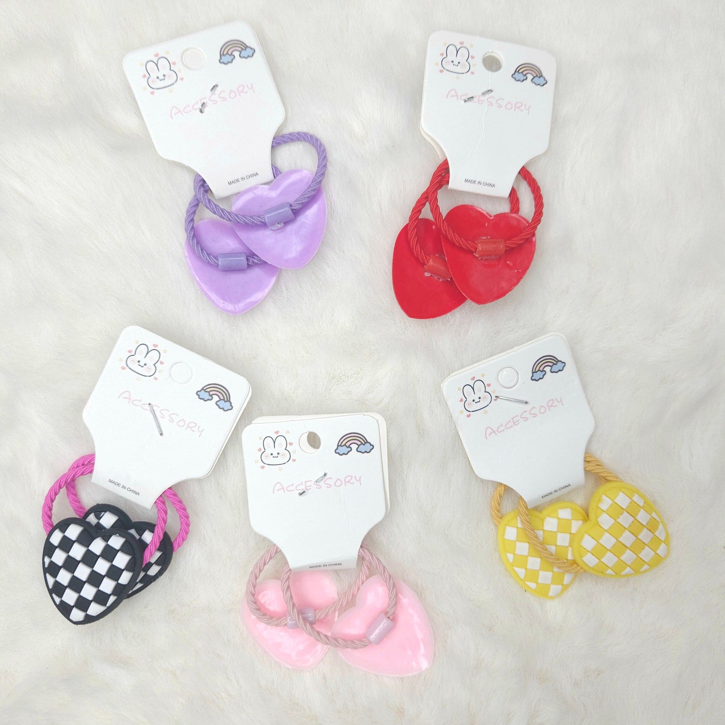 Set of colorful hair ties on white cards with brand name on a light gray background