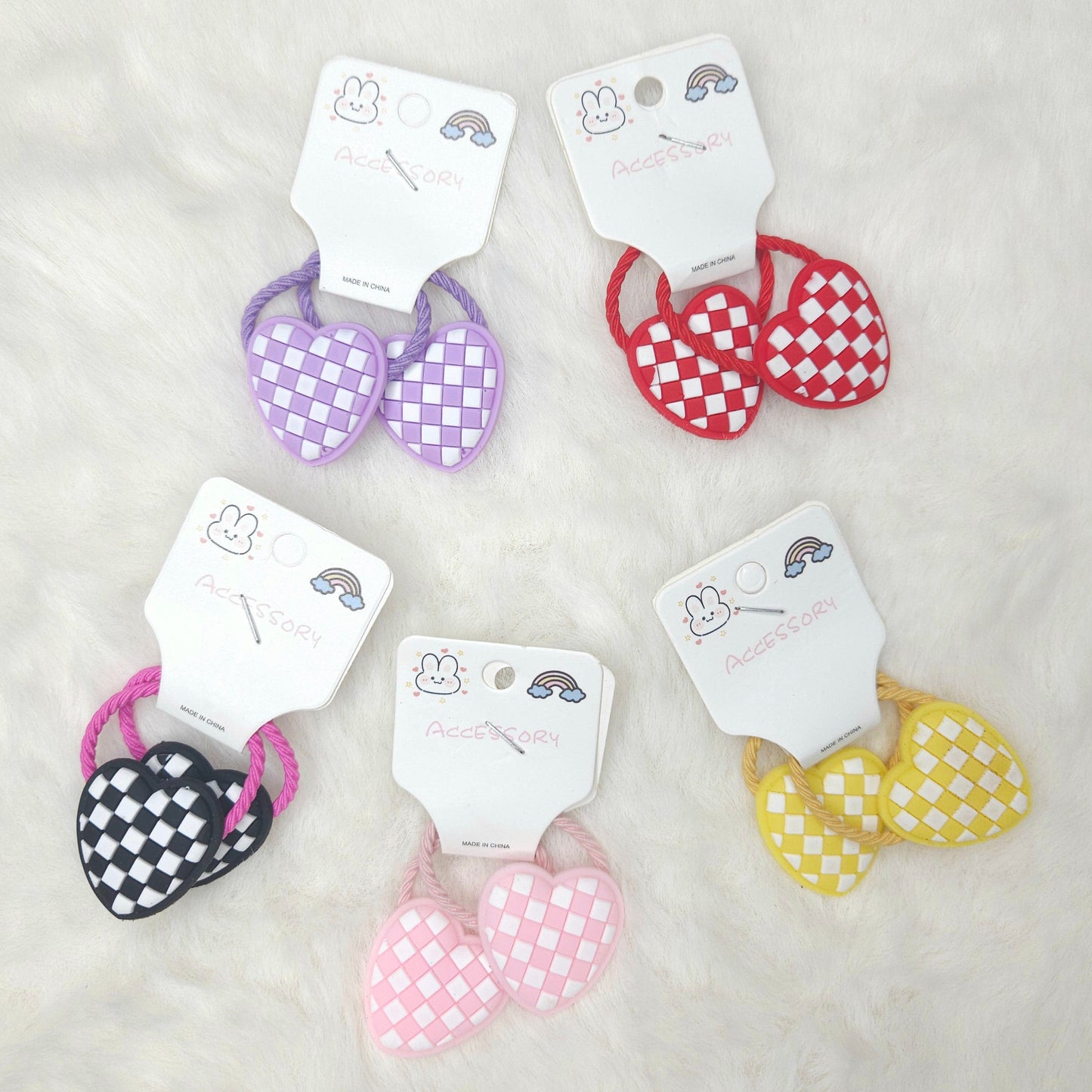 Set of checkered heart-shaped hair ties on white cards with brand name on a light gray background