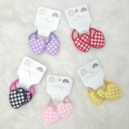 Set of checkered heart-shaped hair ties on white cards with brand name on a light gray background