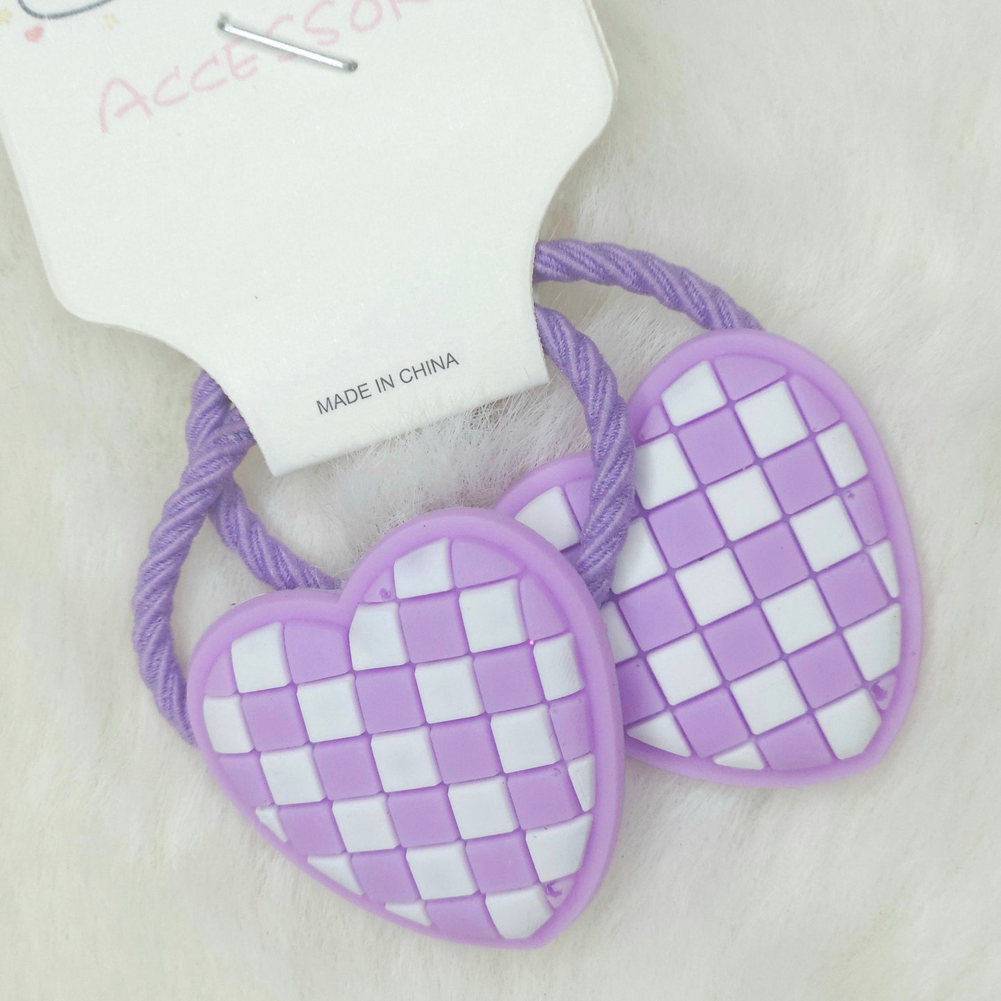Pair of purple checkered hair ties on a beige background