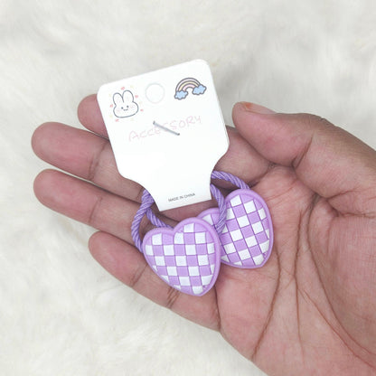 Hand holding two purple woven hair ties with a tag on a white background